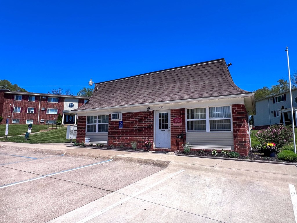 a small brick leasing office with a parking lot in front of it