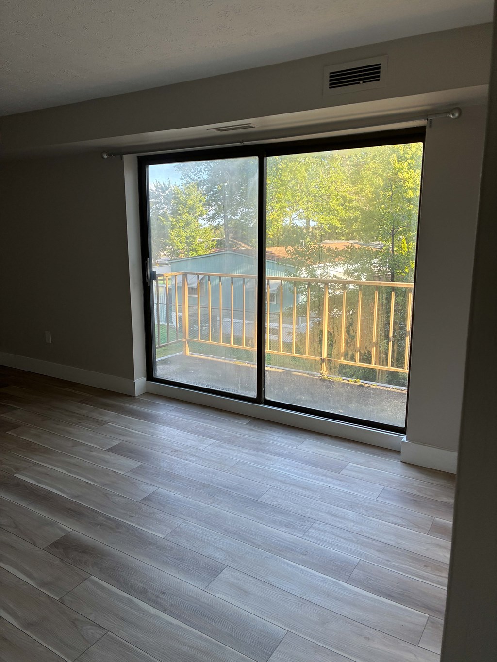 A room with a sliding glass door leading to a balcony.