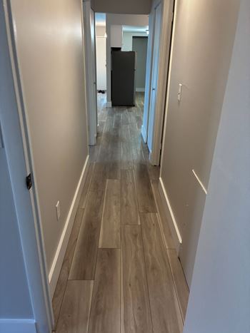 A long hallway with wood floors and white walls.