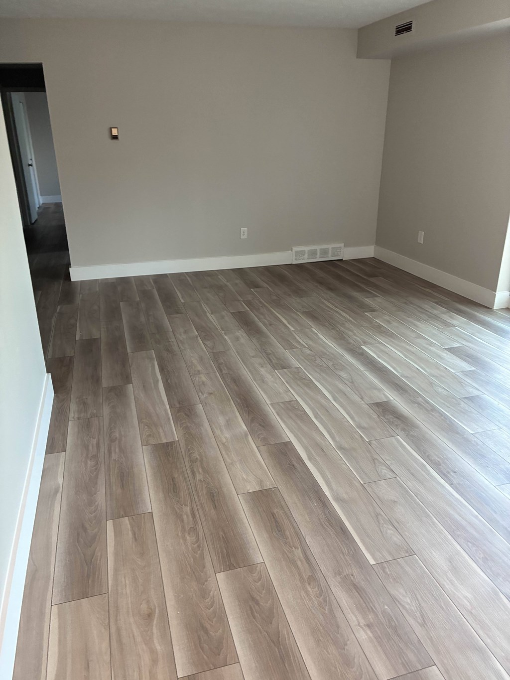 A room with a wood floor and a white wall.