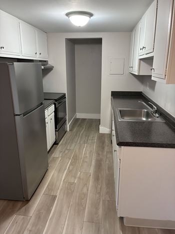 A kitchen with a refrigerator, sink, and cabinets.