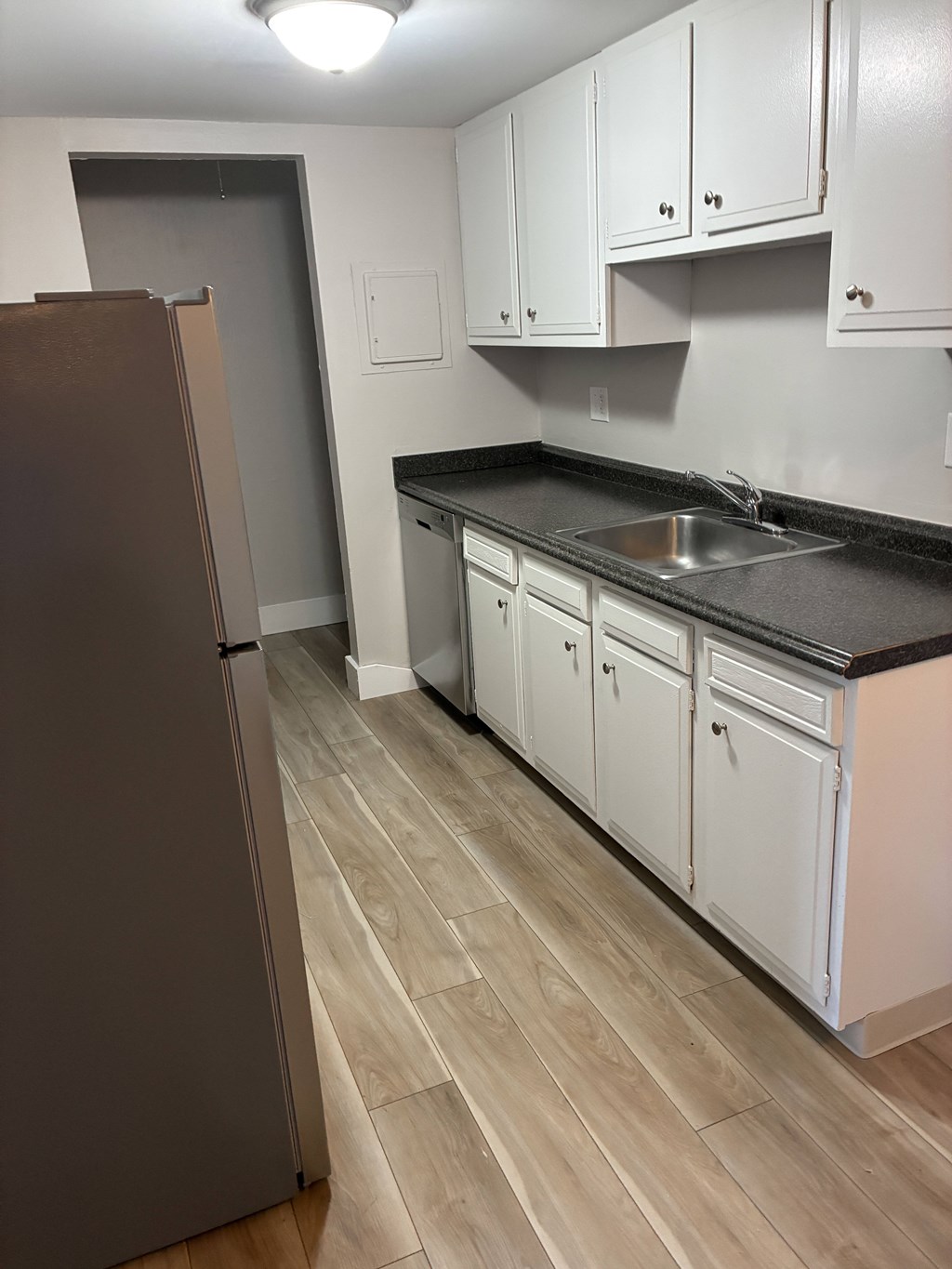 A kitchen with a refrigerator, sink, and cabinets.