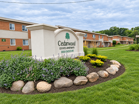 A sign for Cedarwood Estates Apartments sits in front of a building.