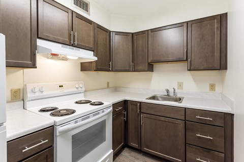 A kitchen with white and brown cabinets and a white stove top oven.