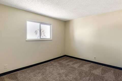 the living room of an empty home with carpet and a window