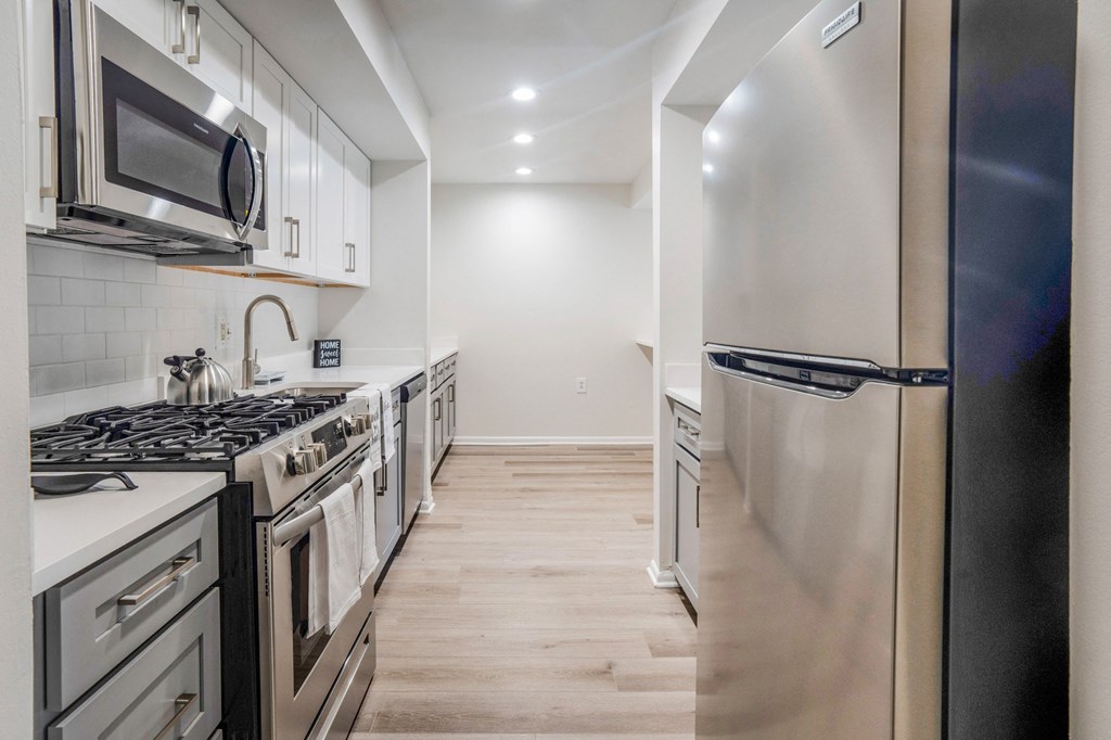 a kitchen with white countertops and stainless steel appliances