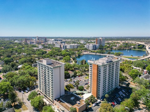 A cityscape with two prominent buildings in the foreground and a body of water in the background.