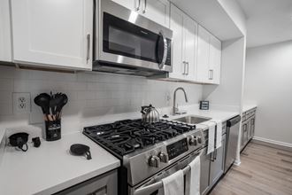 a kitchen with white cabinets and a stainless steel stove top oven