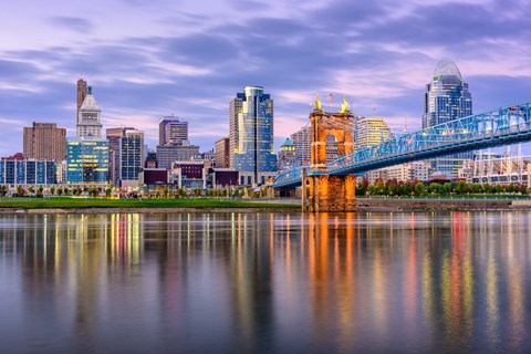 A city skyline with a bridge and buildings reflected in the water.