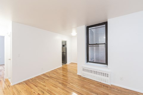 a living room with white walls and wood floors and a window