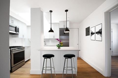 a kitchen with a white counter top and black stools