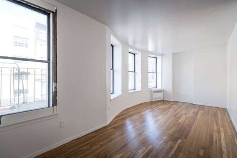 a living room with white walls and wood floors and a window