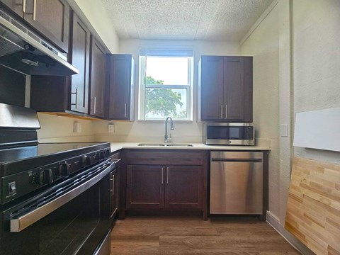 A kitchen with dark wood cabinets and a black stove top oven.