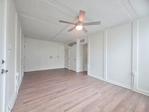 A room with a ceiling fan and wooden flooring.