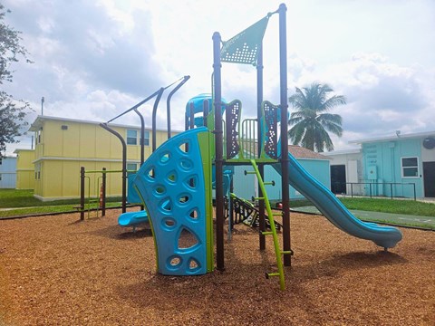 A playground with a blue slide and a green flag.