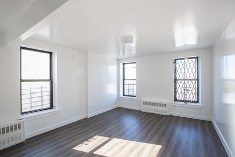 an empty living room with white walls and wood floors and windows