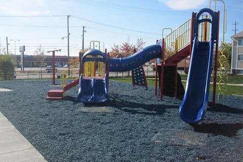 A playground with a blue slide and a yellow railing.