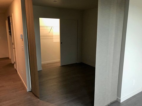 a living room with a hard wood floor and a door to a hallway