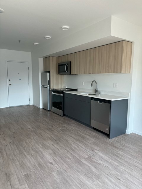 a kitchen in an empty apartment with a sink and refrigerator at Junction Central, Seattle, WA