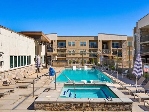 A pool surrounded by sun loungers and umbrellas.