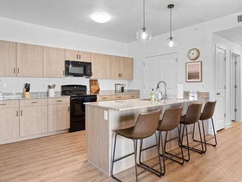 A kitchen with a bar and chairs.
