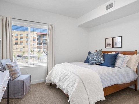 A bedroom with a large bed and a window overlooking a cityscape.