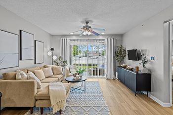 A living room with a beige couch, a black coffee table, and a ceiling fan.