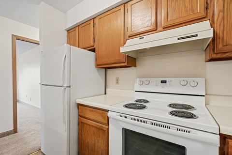 A white stove and refrigerator in a kitchen with wooden cabinets.