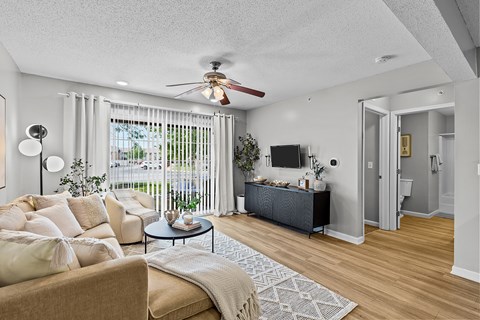 A living room with a beige couch and a ceiling fan.