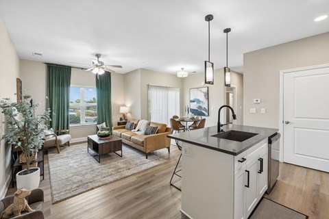 A well-lit, spacious living room with a kitchen area in the background.
