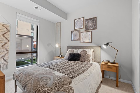 A bedroom with a large bed and a window overlooking a balcony.