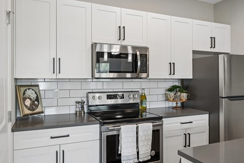 A modern kitchen with white cabinets and stainless steel appliances.