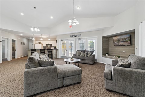 A spacious living room with grey couches and a patterned carpet.