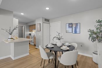 A dining room with a table set for two and a kitchen area