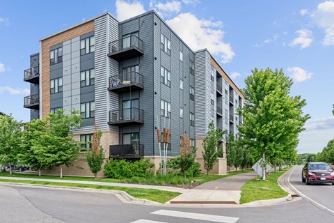 A modern apartment building with balconies and a car on the street.