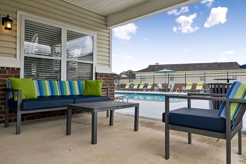 A patio with a table and two chairs with a pool in the background.