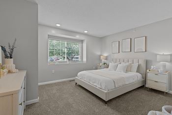 A bedroom with a large bed, nightstand, and a window with a view of the outdoors.