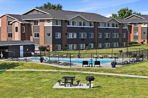 A large apartment complex with a pool and picnic tables.