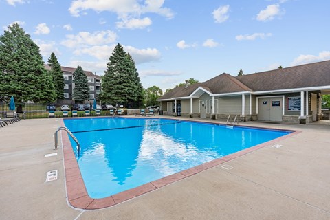 A large swimming pool with a red border and a building in the background.