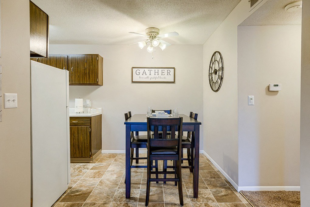 a dining table with blue chairs in a kitchen with a refrigerator