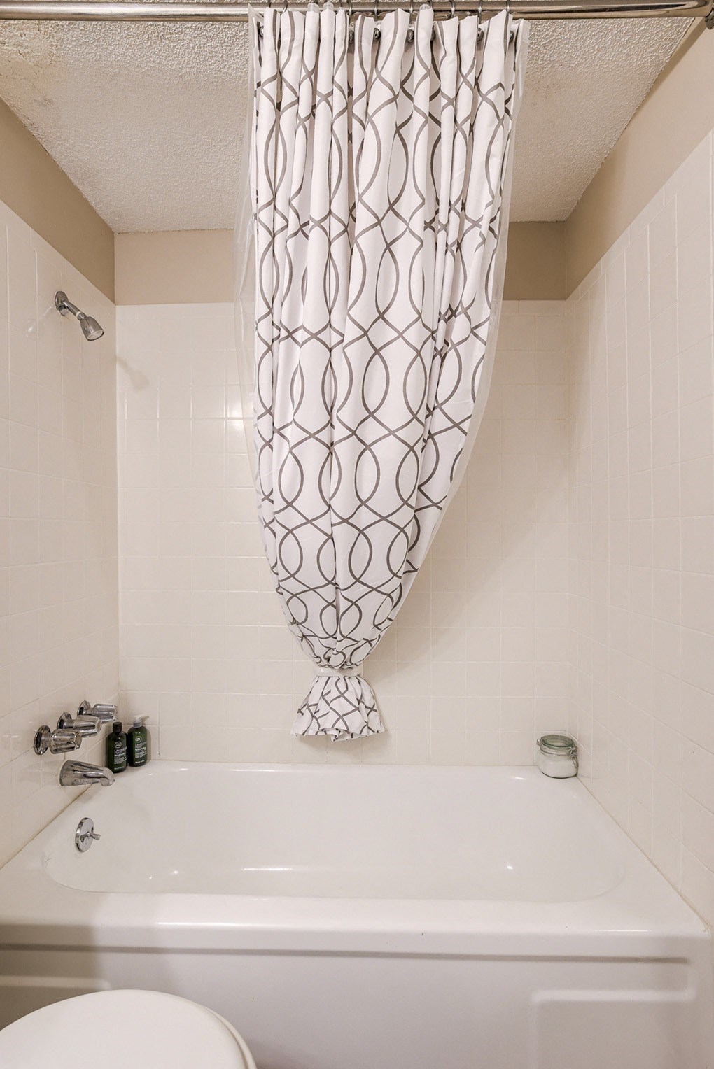 a white bathroom with a shower curtain and a tub
