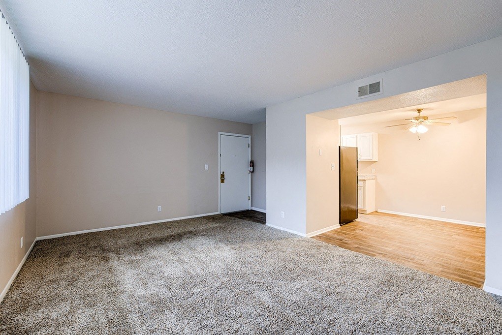 an empty living room with wood flooring and a ceiling fan