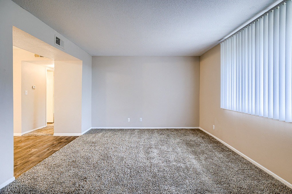 an empty living room with a large window and wood flooring