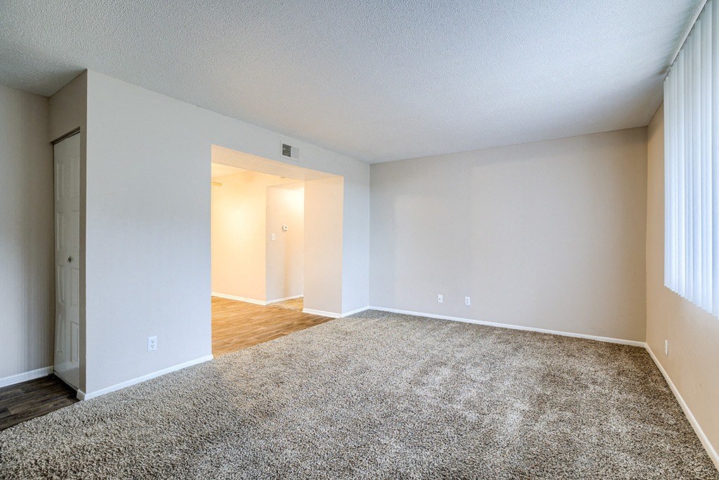 an empty living room with wood flooring and white walls