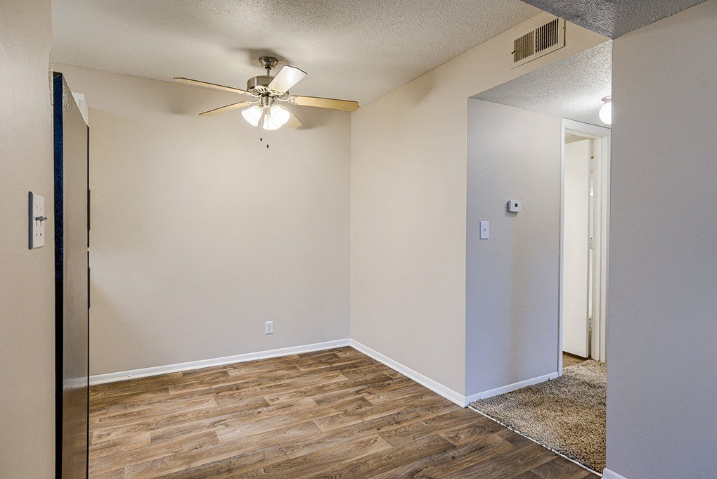 an empty living room with wood flooring and a ceiling fan