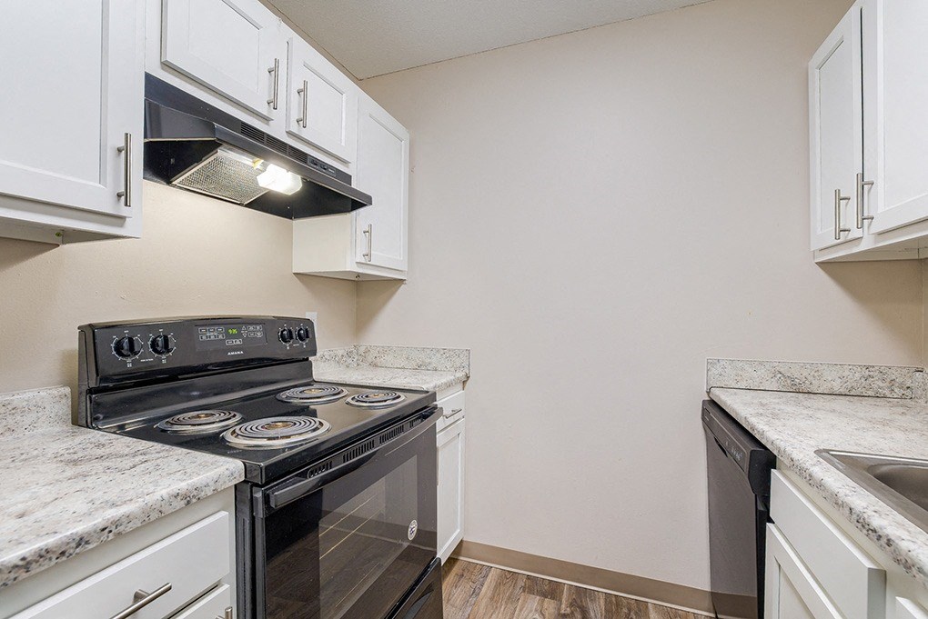 an empty kitchen with white cabinets and a black stove and oven