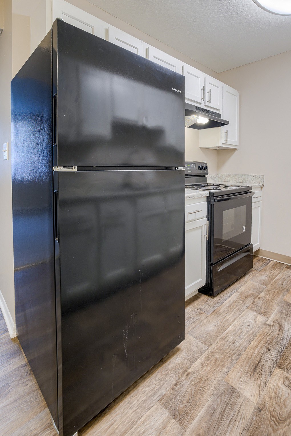 an empty kitchen with a refrigerator and a stove