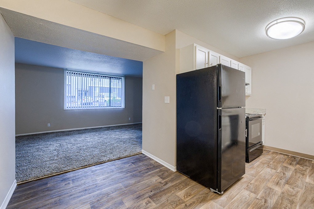 an empty living room with a refrigerator and a window