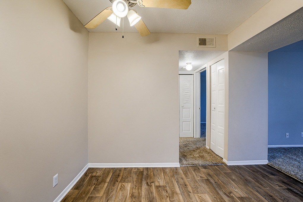 an empty living room with wood flooring and a ceiling fan