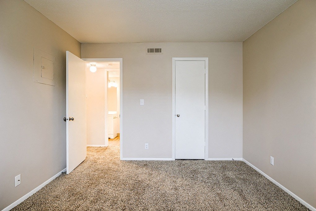 an empty bedroom with a carpeted floor and white doors
